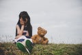 Little girl sitting with her bear upset at meadows field.