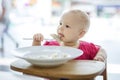 Little girl sitting in high chair and eating dumplings