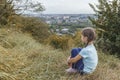 Little girl sitting on a hill above the city. Royalty Free Stock Photo