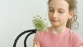 Little girl is sitting at home with flowers in hands during summer time and sneezing, hypersensitivity, asthma, or