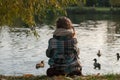 A little girl sitting on a lake side, looking at the water and feeding ducks Royalty Free Stock Photo