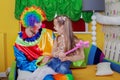 Little girl sitting on the lap of a cheerful clown