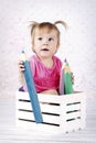 Little girl sitting in the little box with big coloring pencils Royalty Free Stock Photo