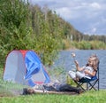 Little girl sitting near campfire. Girl roasting bread over campfire