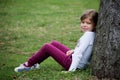 Little girl is sitting near the tree on meadow Royalty Free Stock Photo