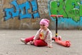 A little girl sitting next to a children`s scooter in a skate Park Royalty Free Stock Photo