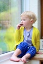 Little girl sitting next window on rainy day Royalty Free Stock Photo