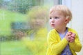 Little girl sitting next window on rainy day Royalty Free Stock Photo