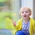Little girl sitting next window on rainy day Royalty Free Stock Photo