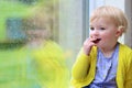 Little girl sitting next window on rainy day Royalty Free Stock Photo