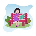 A little girl sitting on a park bench enjoying reading a book Royalty Free Stock Photo
