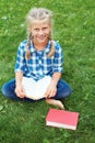 Little girl is sitting reading on the grass.