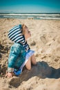 Little girl sitting on the sand at the beach