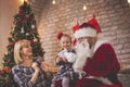 Little girl sitting in Santas lap, giving him a drawing