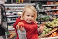 Little girl sitting in shopping cart in food fruit store or supermarket Royalty Free Stock Photo