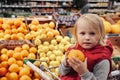 Little girl sitting in shopping cart in food fruit store or supermarket Royalty Free Stock Photo