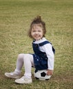 Little girl sitting on a soccer ball.