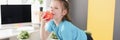 Little girl sitting on sofa and eating red apple at home Royalty Free Stock Photo