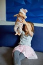 Little girl sitting on the sofa in the room at home playing with baby doll Royalty Free Stock Photo