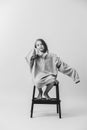 Little girl sitting on the stepping stool in a huge oversized longsleeve