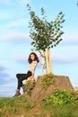 Little girl sitting on stump by new linden Royalty Free Stock Photo