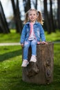 Little girl sitting on a stump in the park Royalty Free Stock Photo