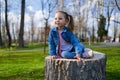 Little girl sitting on a stump in the park Royalty Free Stock Photo