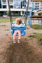 Little girl sitting on a swing in the playground, turning her head back Royalty Free Stock Photo