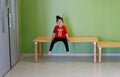 Little girl sitting on a table next to her classroom door Royalty Free Stock Photo