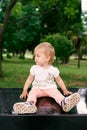 Little girl sitting on a tile in a green park