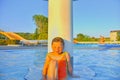 Little girl sitting under a sprinkler, shower in swimming pool. Portrait of little cute girl in the swimming pool. Sunny summer da Royalty Free Stock Photo