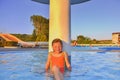 Little girl sitting under a sprinkler, shower in swimming pool. Portrait of little cute girl in the swimming pool. Sunny summer da Royalty Free Stock Photo