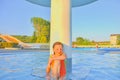 Little girl sitting under a sprinkler, shower in swimming pool. Portrait of little cute girl in the swimming pool. Sunny summer da Royalty Free Stock Photo