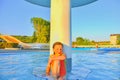 Little girl sitting under a sprinkler, shower in swimming pool. Portrait of little cute girl in the swimming pool. Sunny summer da Royalty Free Stock Photo
