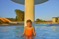 Little girl sitting under a sprinkler, shower in swimming pool. Portrait of little cute girl in the swimming pool. Sunny summer da Royalty Free Stock Photo