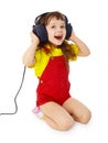 Little girl sitting on white with large earpieces Royalty Free Stock Photo