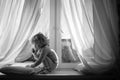 Little girl sitting by the window