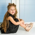 A little girl is sitting on the window on the background of the Royalty Free Stock Photo