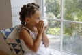 Little girl sitting by the window with a cup of hot drink and looking outdoors Royalty Free Stock Photo