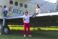 A little girl is sitting on the wing of a private airplane