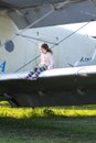 A little girl is sitting on the wing of a private airplane