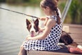 Girl sitting on a wood pier and enjoying with her dog Royalty Free Stock Photo