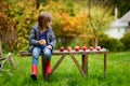 Little girl sitting on a wooden bench on autumn