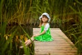 Little girl sitting on wooden bridge across river Royalty Free Stock Photo