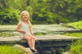 Little girl sitting an wooden bridge and laughing Royalty Free Stock Photo