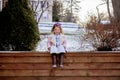 Little girl sitting on wooden planks and reading the bible in a garden covered in the snow Royalty Free Stock Photo