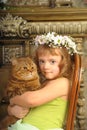 Little girl sitting with a wreath of flowers on her head with a big fat cat Royalty Free Stock Photo