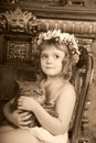 Little girl sitting with a wreath of flowers on her head with a big fat cat Royalty Free Stock Photo