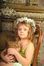 Little girl sitting with a wreath of flowers on her head with a big fat cat Royalty Free Stock Photo