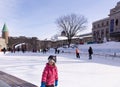 Little girl skating on the DÃ¢â¬â¢Youville Square ice rink with other people and the Saint John Gate